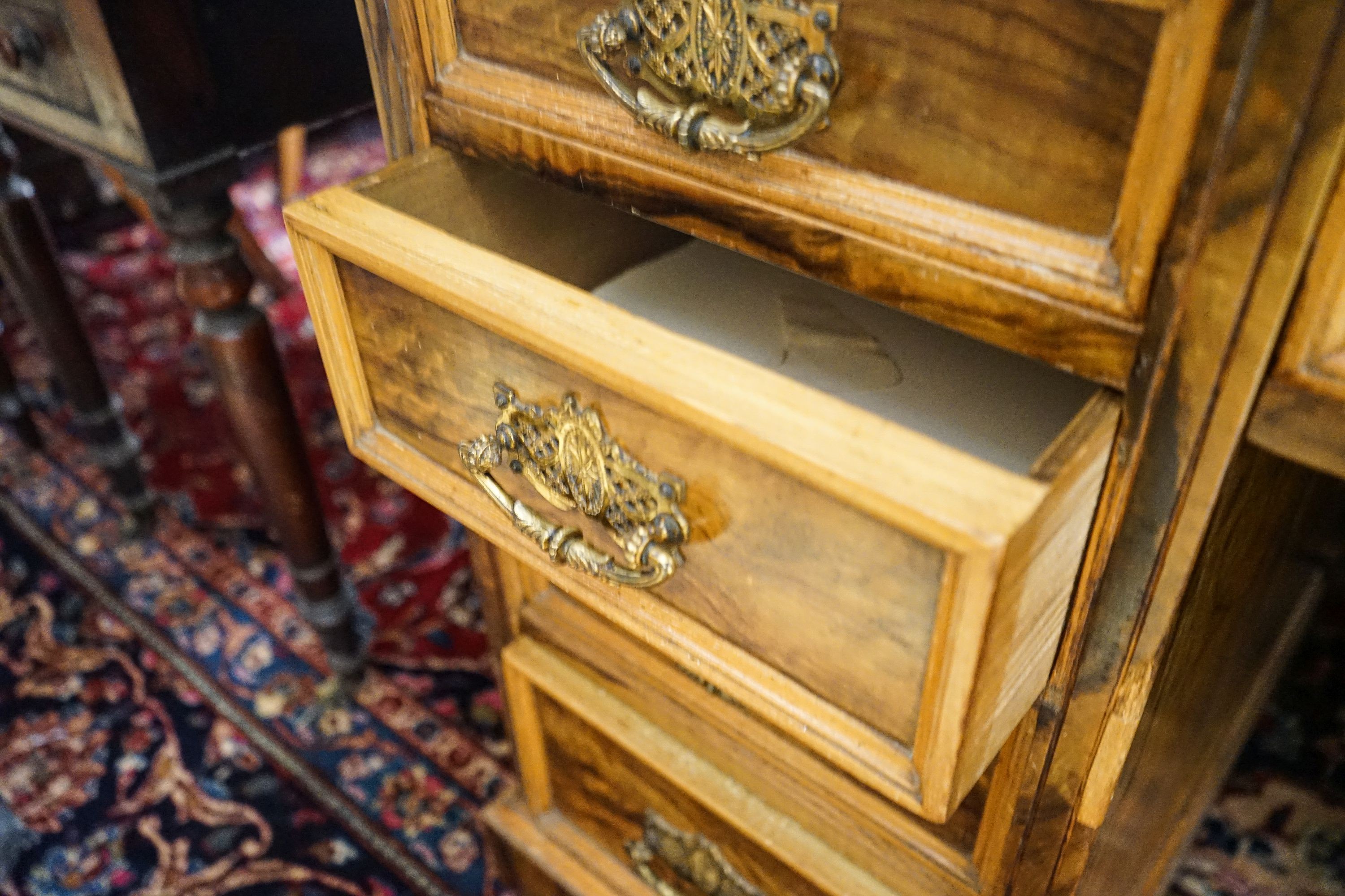 A late Victorian figured walnut twin pedestal desk, fitted with nine drawers with decorative gilt brass handles and plinth base, length 121cm, depth 60cm, height 75cm